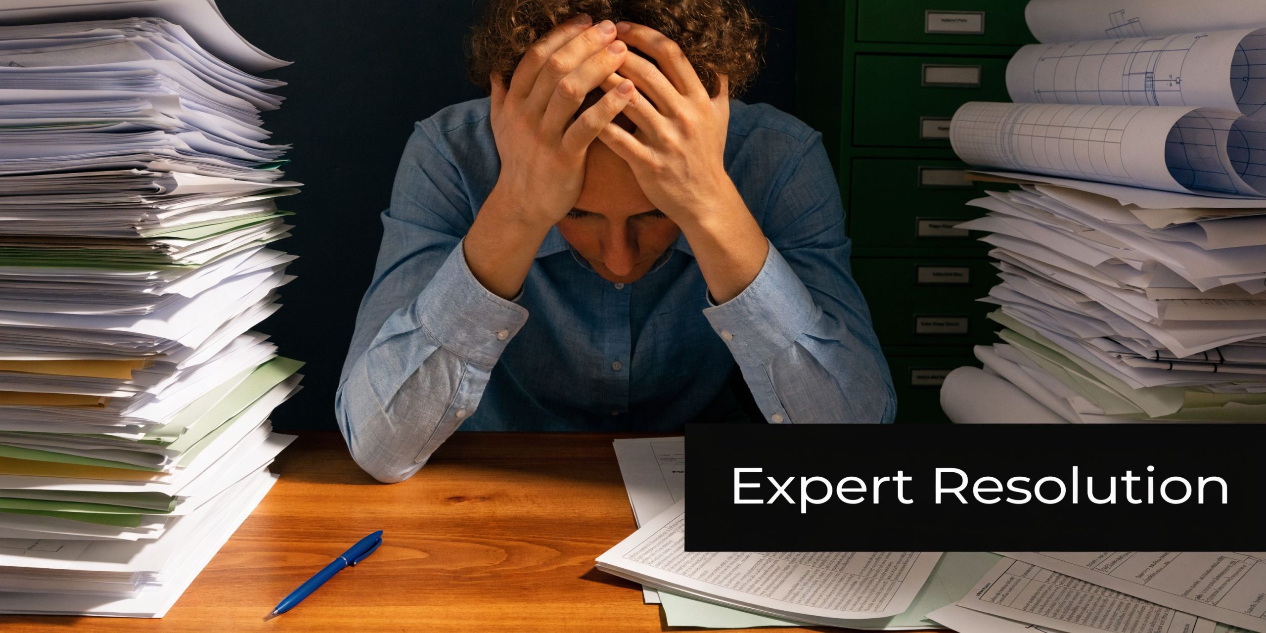 A person sitting at a desk with large stacks of documents feeling overwhelmed by construction paperwork.