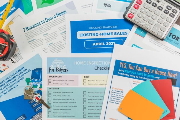 A collage of real estate flyers and documents, including a blue 'Existing-Home Sales' card, inspection checklists, and a calculator with a colorful spread of pamphlets.